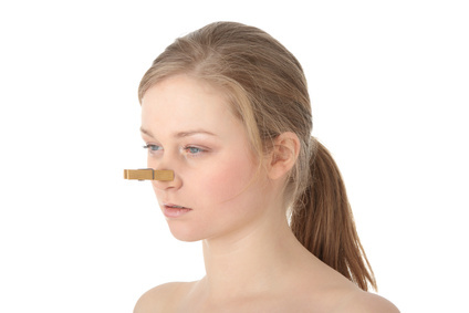 Disgusted woman with clothespin clipped to nose